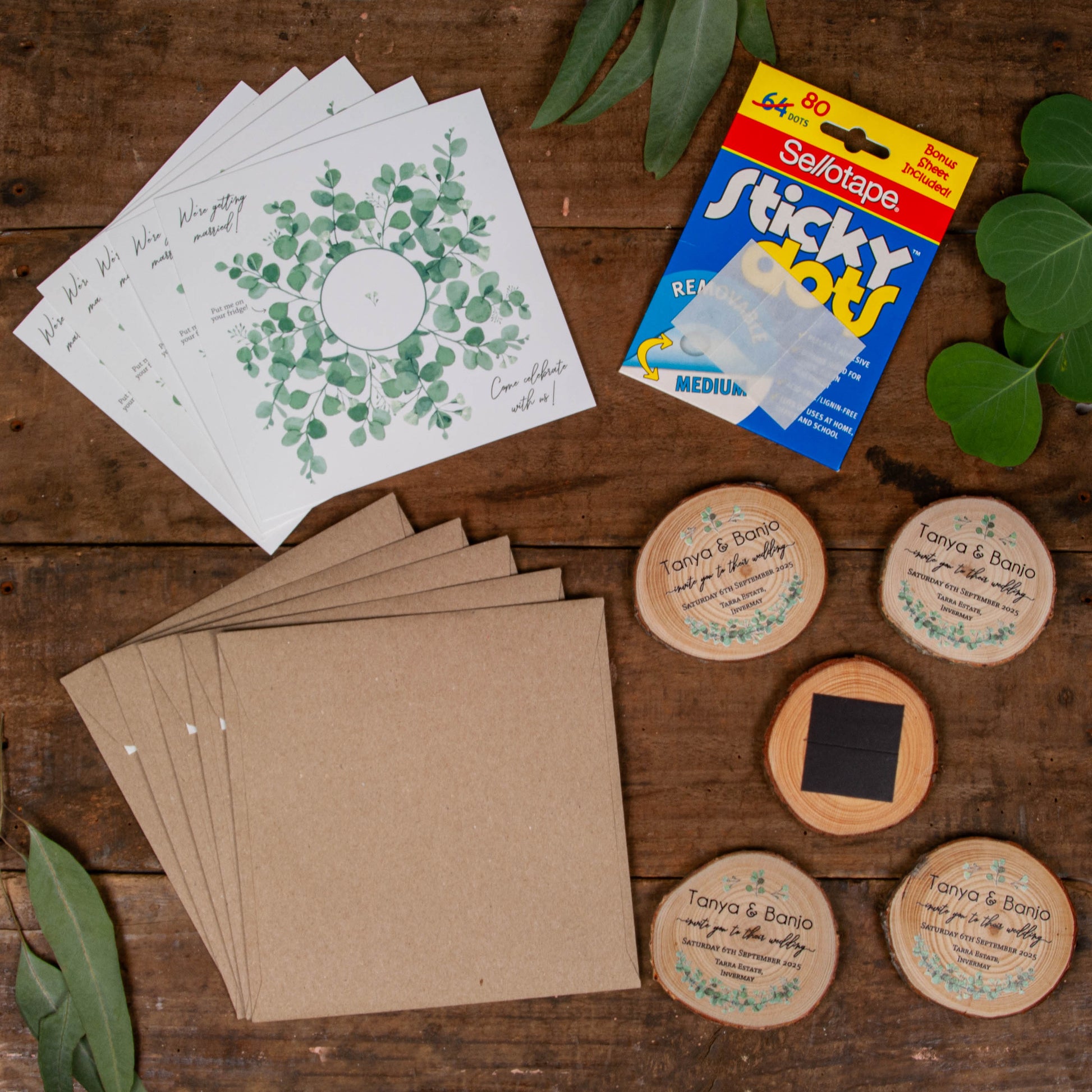 Top down view of wood slice invitation pack including wood slice magnet, card, envelope and sticky dots