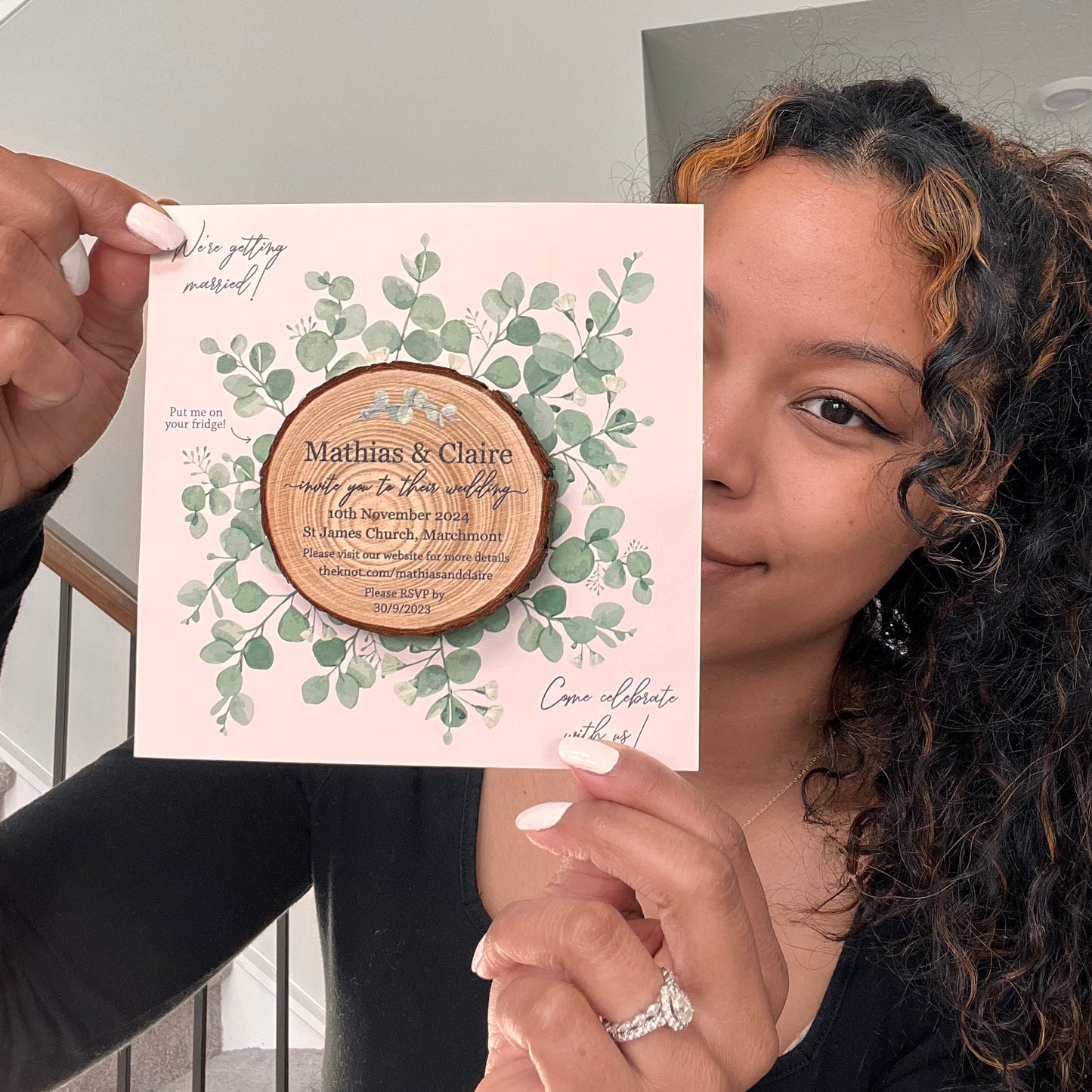 person holding wood slice invite with eucalyptus card